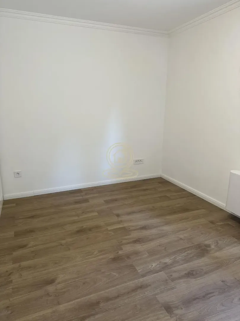 Empty room with white walls and laminate flooring.