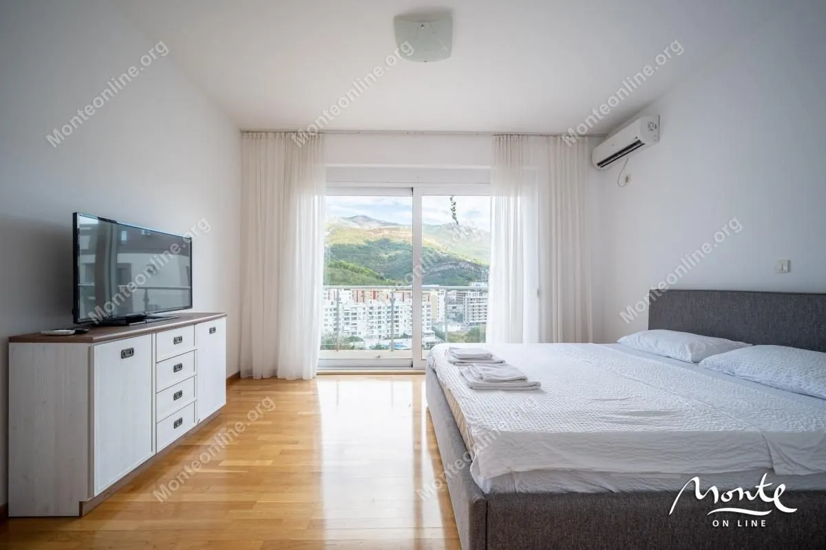 Furnished bedroom with a double bed, dresser, and balcony access.