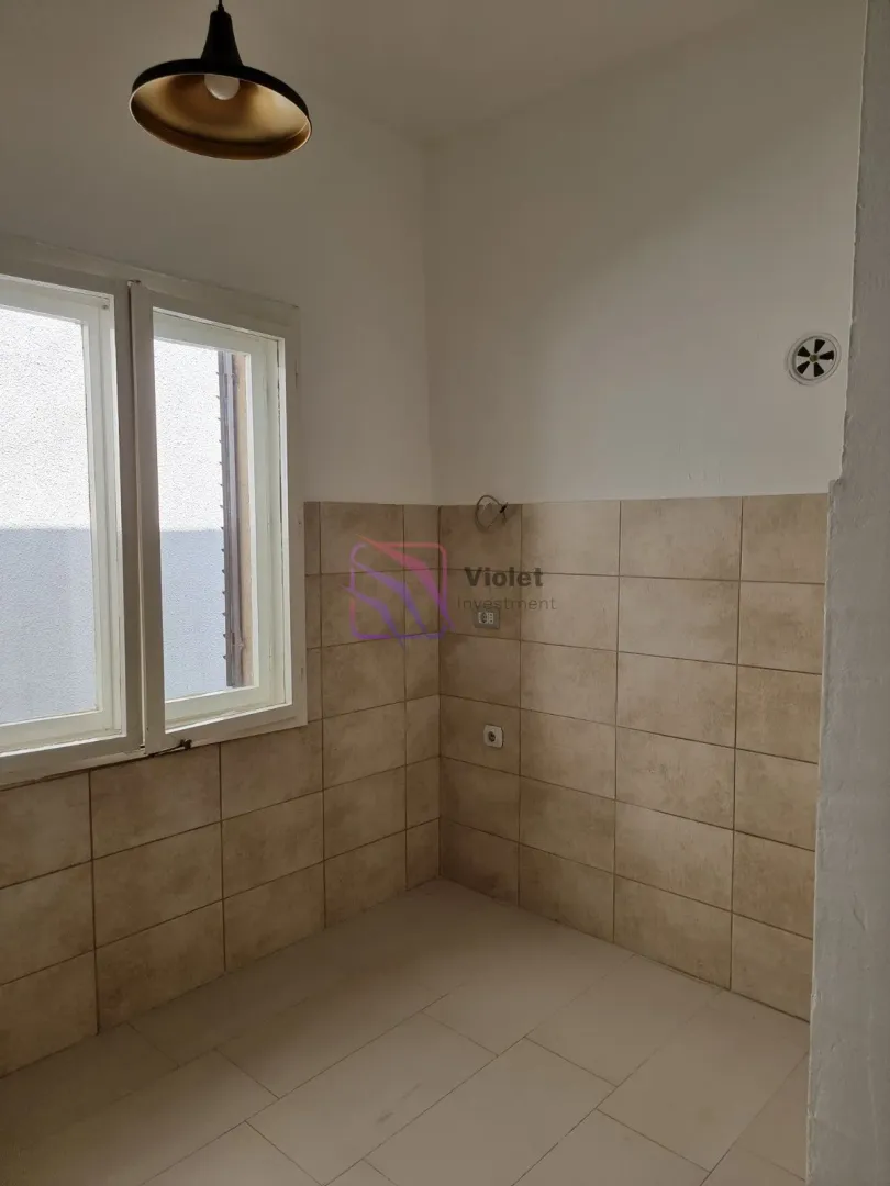 Empty kitchen with wall tiles and a window.