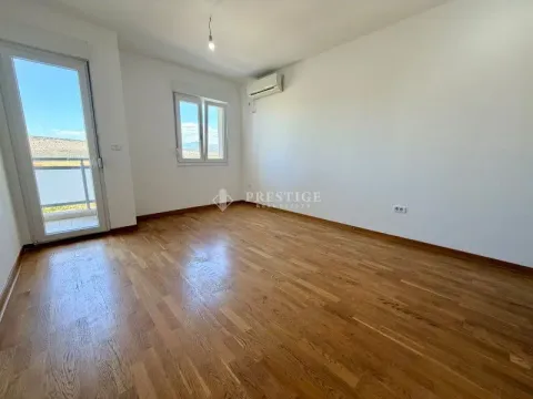 Prazna soba sa drvenim podom, klima uređajem i izlazom na terasu. - image 2