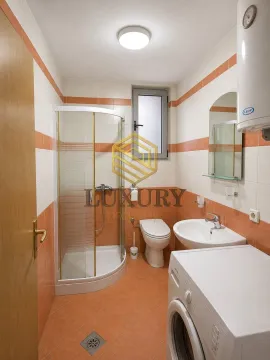 Bathroom equipped with a shower cabin, washbasin, toilet, and washing machine. - image 5