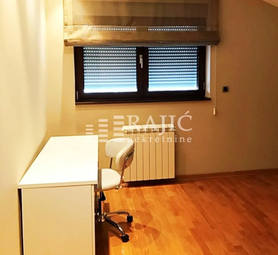 Study room with a desk and a window with blinds.