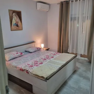 Spavaća soba sa bračnim krevetom, noćnim stočićem i klima uređajem. - image 2