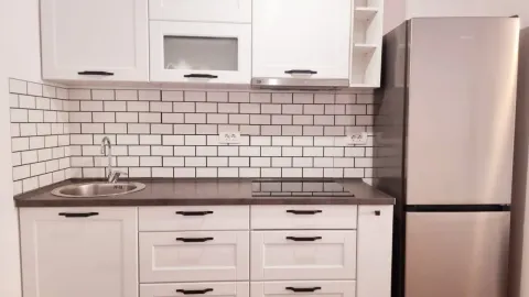 Bijela kuhinja sa sudoperom, pločom za kuvanje i frižiderom. - image 4