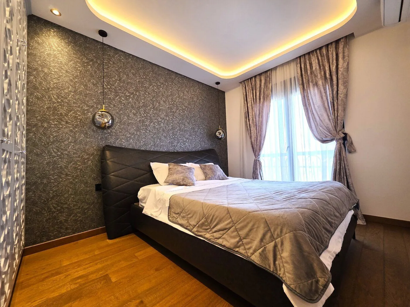 Modern bedroom with a double bed, decorative lighting, and wooden flooring.
