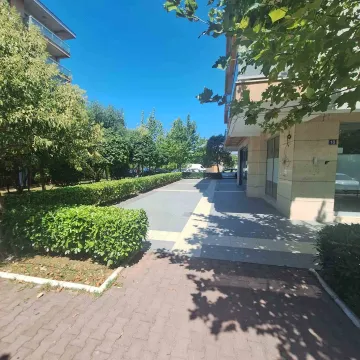 View of the landscaped courtyard in front of the building with greenery and paved paths. - image 7
