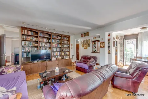Living room with a large wooden bookcase, seating furniture, and a television. - image 2