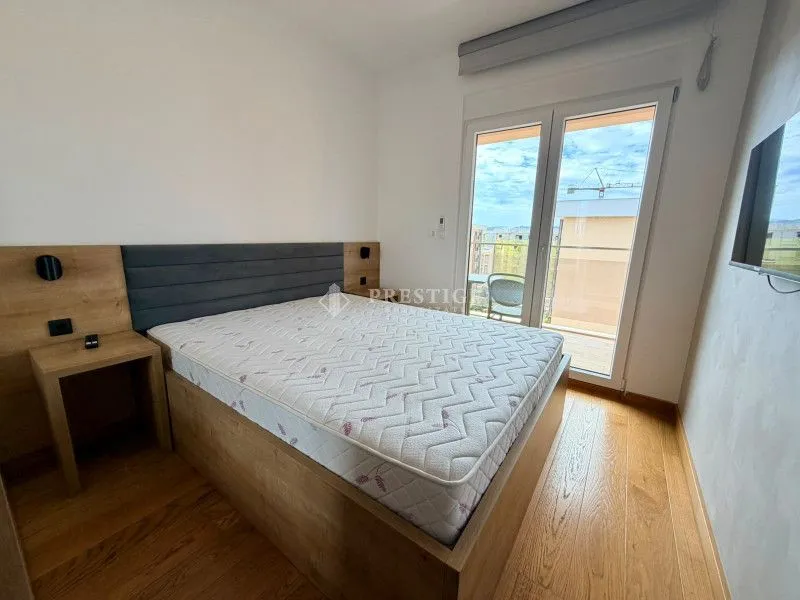 Svijetla spavaća soba sa bračnim krevetom i izlazom na terasu.