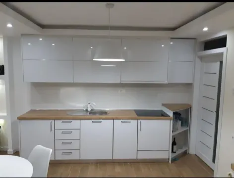 Moderna bijela kuhinja sa drvenom radnom površinom i visećim elementima. - image 6