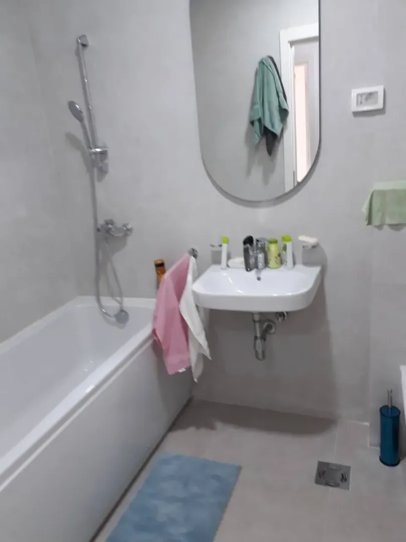 Smaller bathroom with a bathtub, washbasin, and mirror.