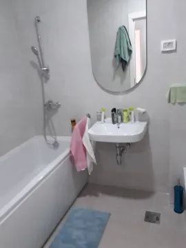 Smaller bathroom with a bathtub, washbasin, and mirror. - image 6