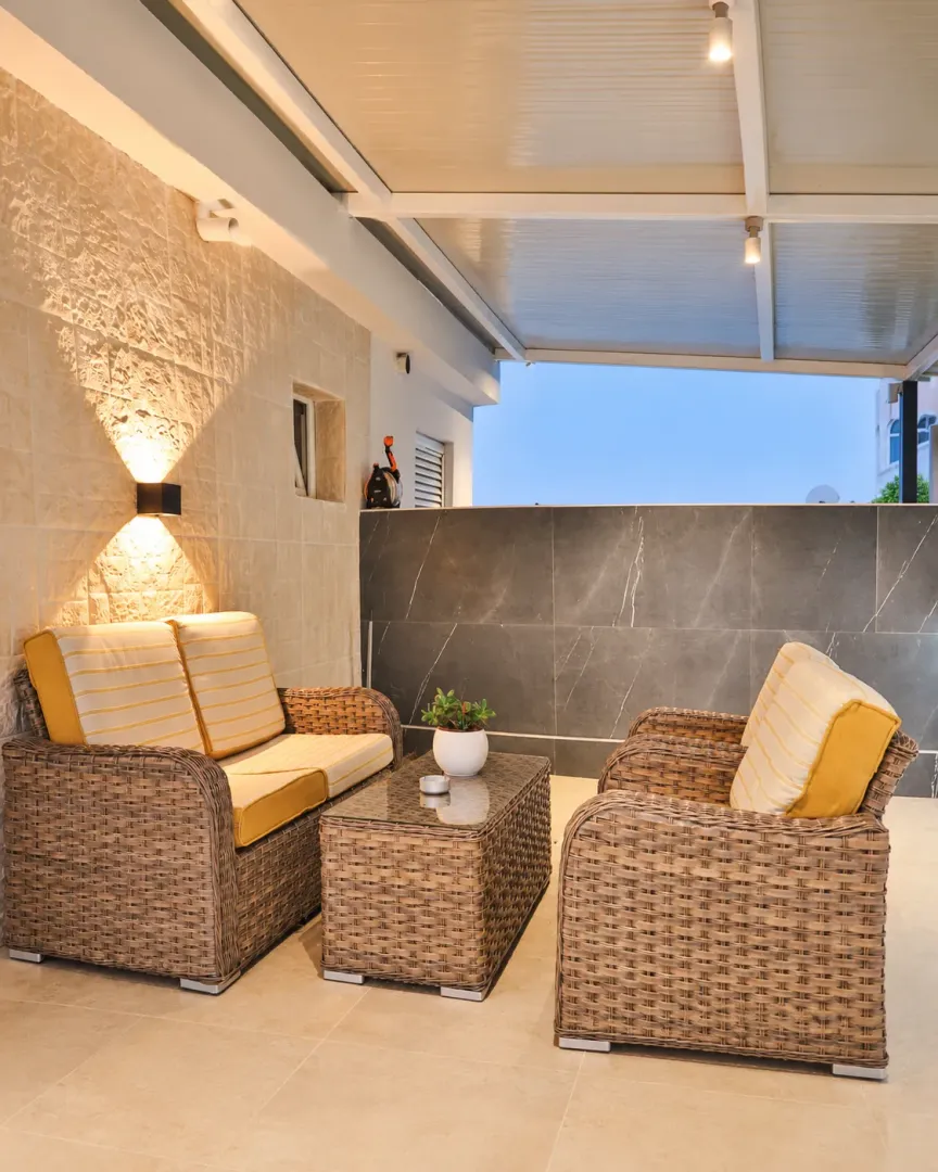 Covered terrace with seating furniture and lighting.