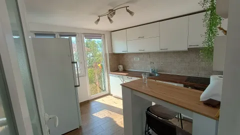 Kuhinja sa bijelim elementima, drvenom radnom pločom i šankom. - image 4