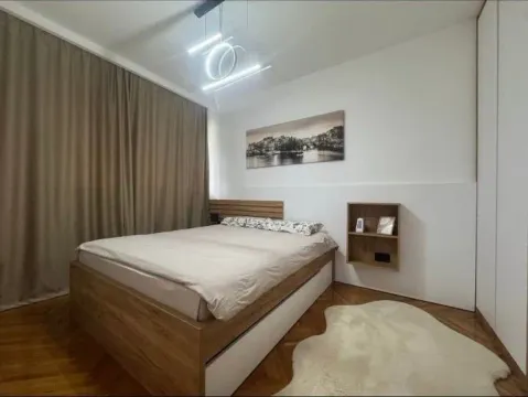 Modern bedroom with a double bed, wooden flooring, and lighting. - image 3