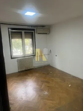 Prazna soba sa drvenim parketom, prozorom i radijatorom. - image 2