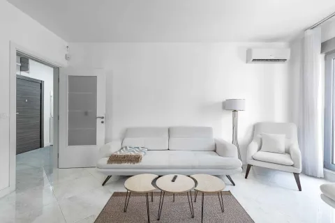 Bright living room with a white sofa, armchair, and modern coffee tables. - image 8