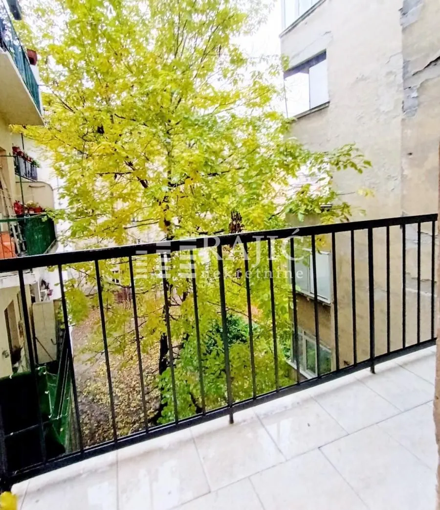 View from the balcony overlooking trees and surrounding buildings.