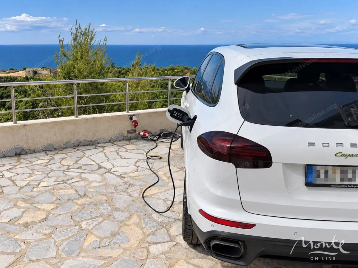 Automobil parkiran na popločanom dvorištu sa pogledom na more.
