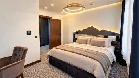 Moderna spavaća soba sa bračnim krevetom, tapaciranom foteljom i modernom rasvetom. - image 5