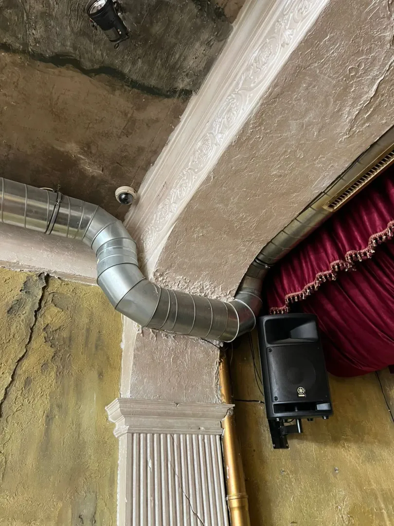 Interior detail showing ventilation pipes, a speaker, and decorative elements on the wall.