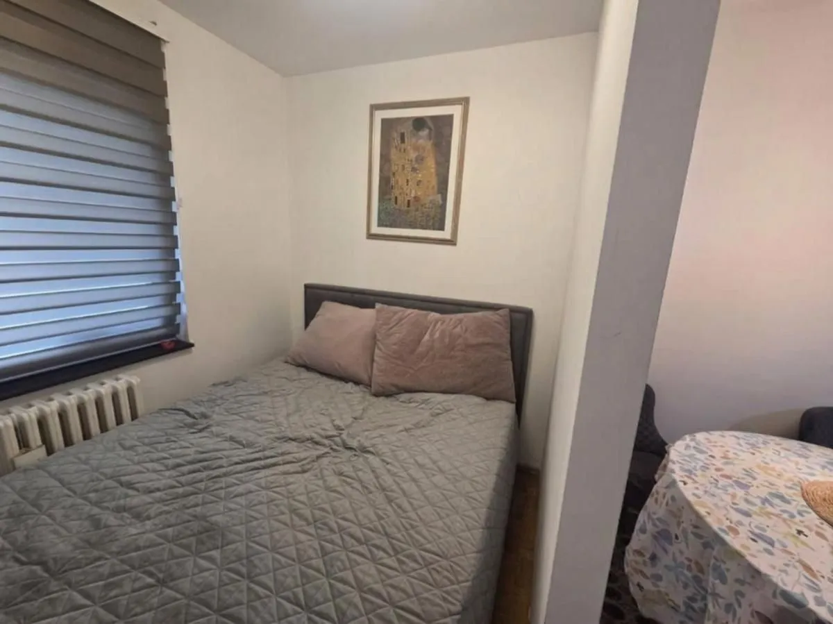 Manja spavaća soba sa bračnim krevetom i prozorom.