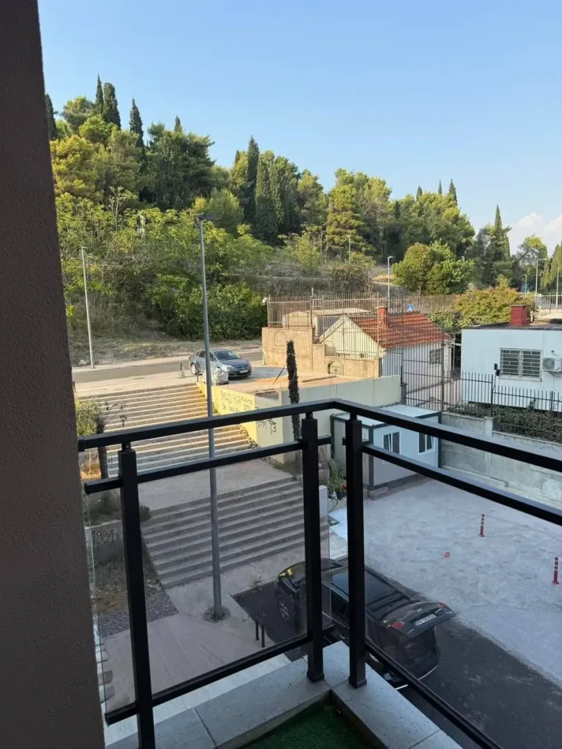 View from the balcony overlooking the yard, street, and surrounding greenery.