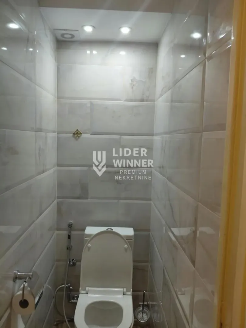 Manje kupatilo obloženo keramičkim pločicama sa WC šoljom.