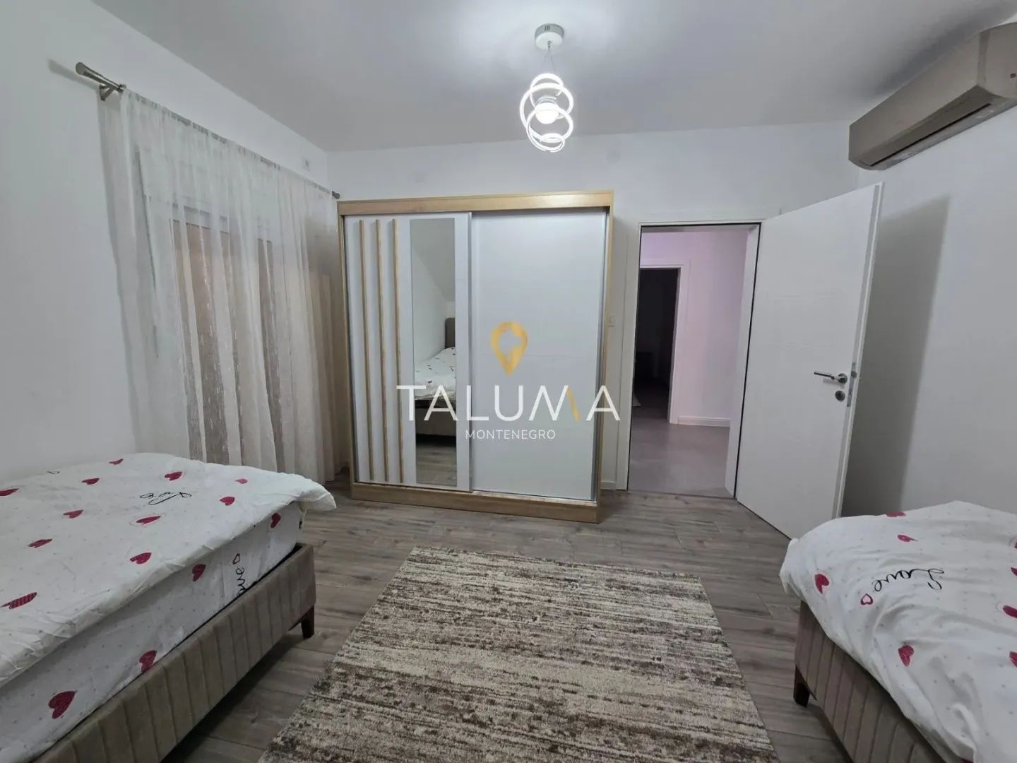 Furnished bedroom with two single beds, a large wardrobe, and a rug.