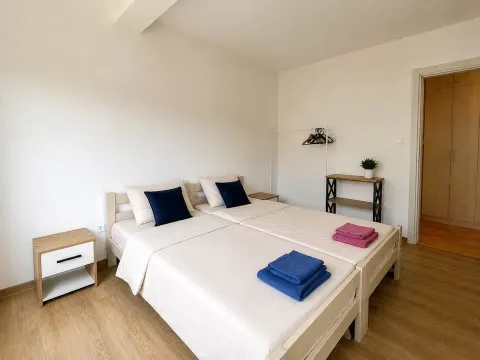 Svijetla spavaća soba sa dva spojena kreveta i noćnim stočićima. - image 6