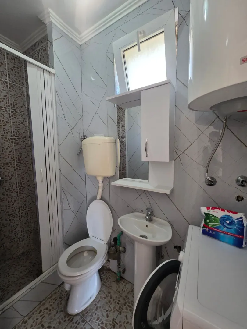 Smaller bathroom with a shower cabin, toilet, washbasin, and water heater.