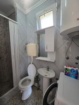 Smaller bathroom with a shower cabin, toilet, washbasin, and water heater. - image 16