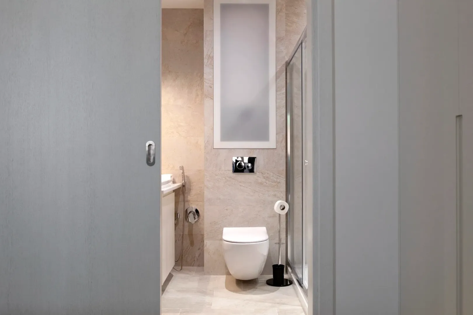 View through the open door into a modernly furnished bathroom with a shower cabin.
