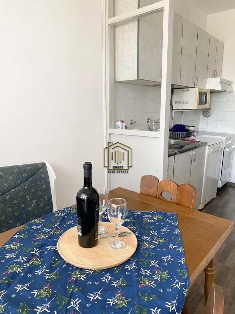 Dining table with a bottle of wine and glasses near the kitchen.