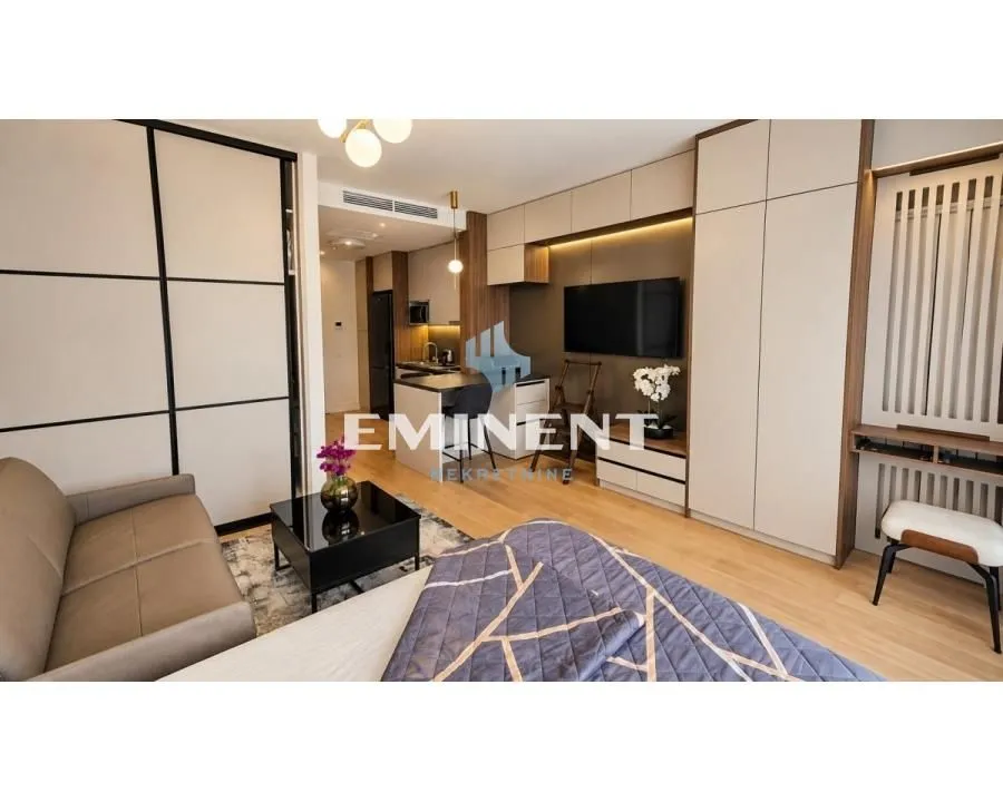 Modern bedroom with a double bed, sofa, and built-in wardrobes.