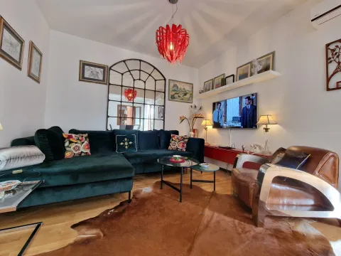 Dnevna soba sa udobnom tamnozelenom ugaonom garniturom, kožnom foteljom i televizorom na zidu. - image 13