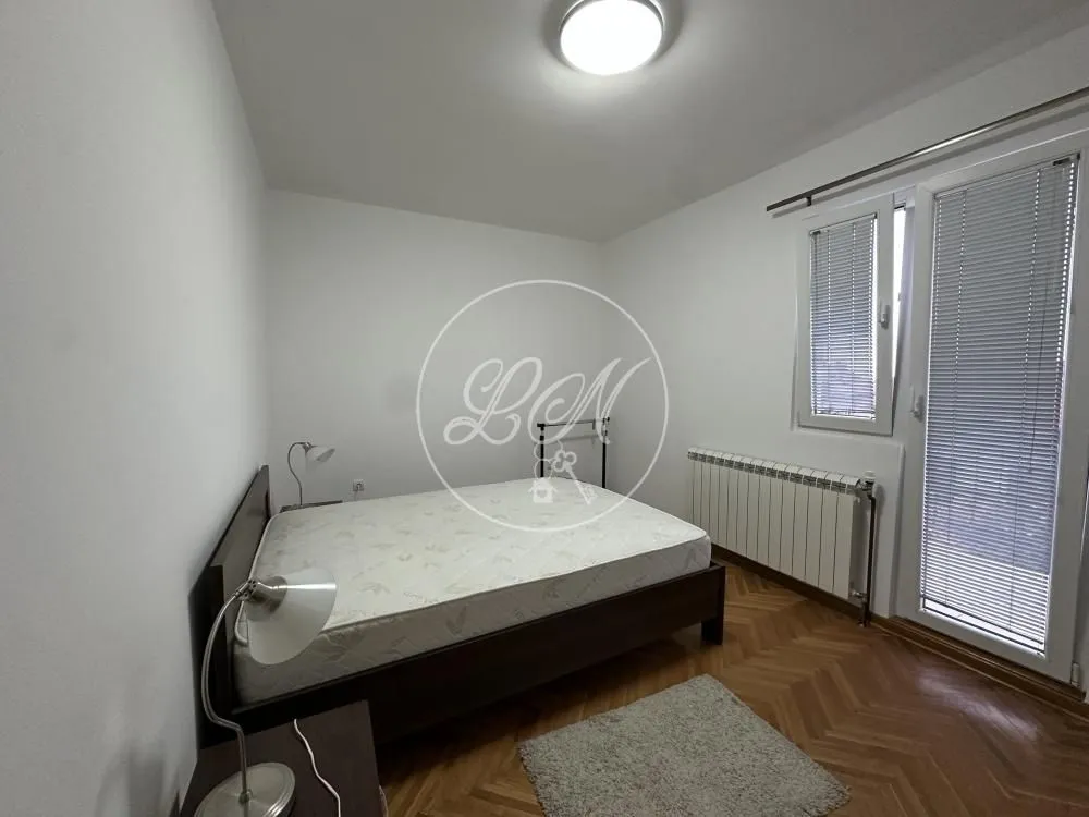Furnished bedroom with a double bed and parquet flooring.