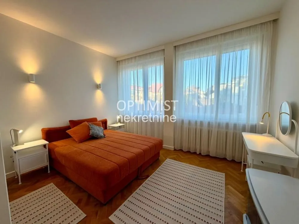 Spacious bedroom with a double bed, desk, and large windows.