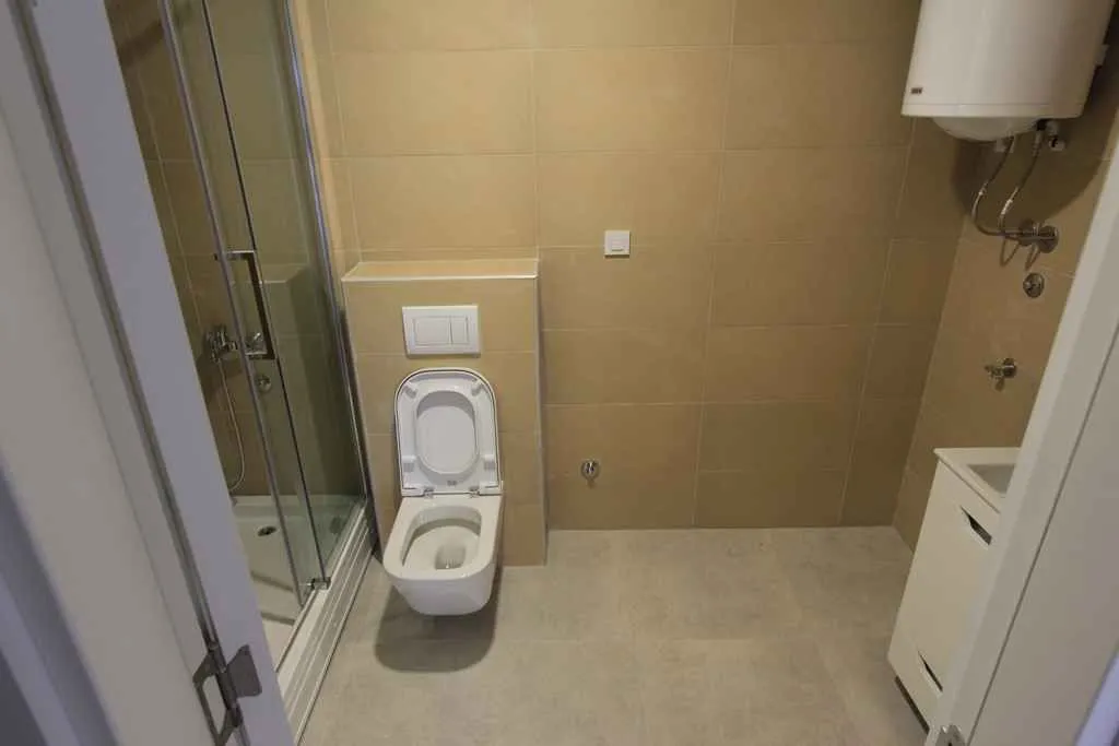Manje kupatilo sa tuš kabinom, WC šoljom i manjim umivaonikom.