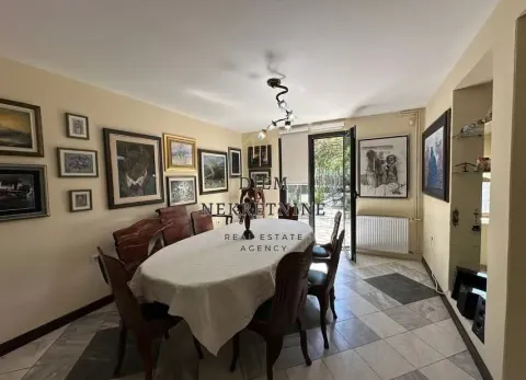 Dining room with a large table and chairs, decorated with art paintings on the walls. - image 9
