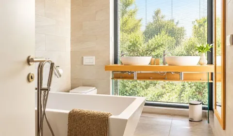 Modern bathroom with a bathtub, double sink and a large window overlooking greenery. - image 16