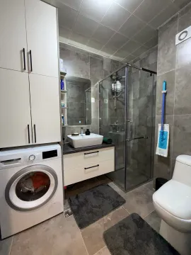 Kupatilo opremljeno tuš kabinom, umivaonikom, WC šoljom i mašinom za pranje veša. - image 7