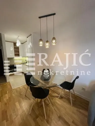 Dining area with a glass table and chairs, connected to the kitchen.