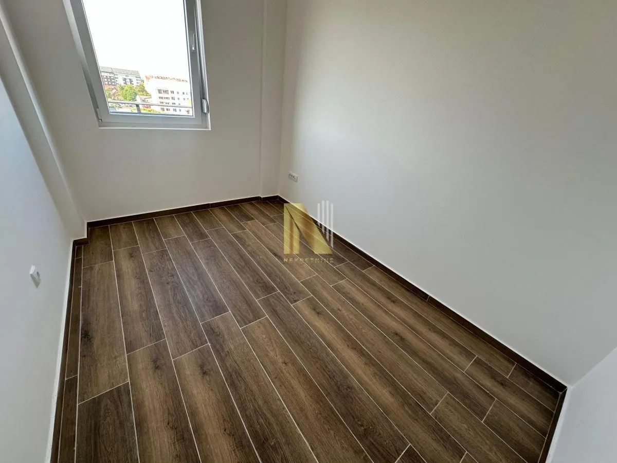 Prazna soba sa drvenim podom i prozorom.