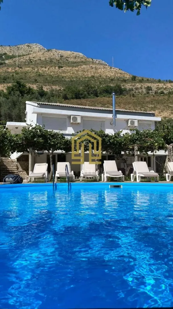 Exterior of the house with a swimming pool and sun loungers in the yard.
