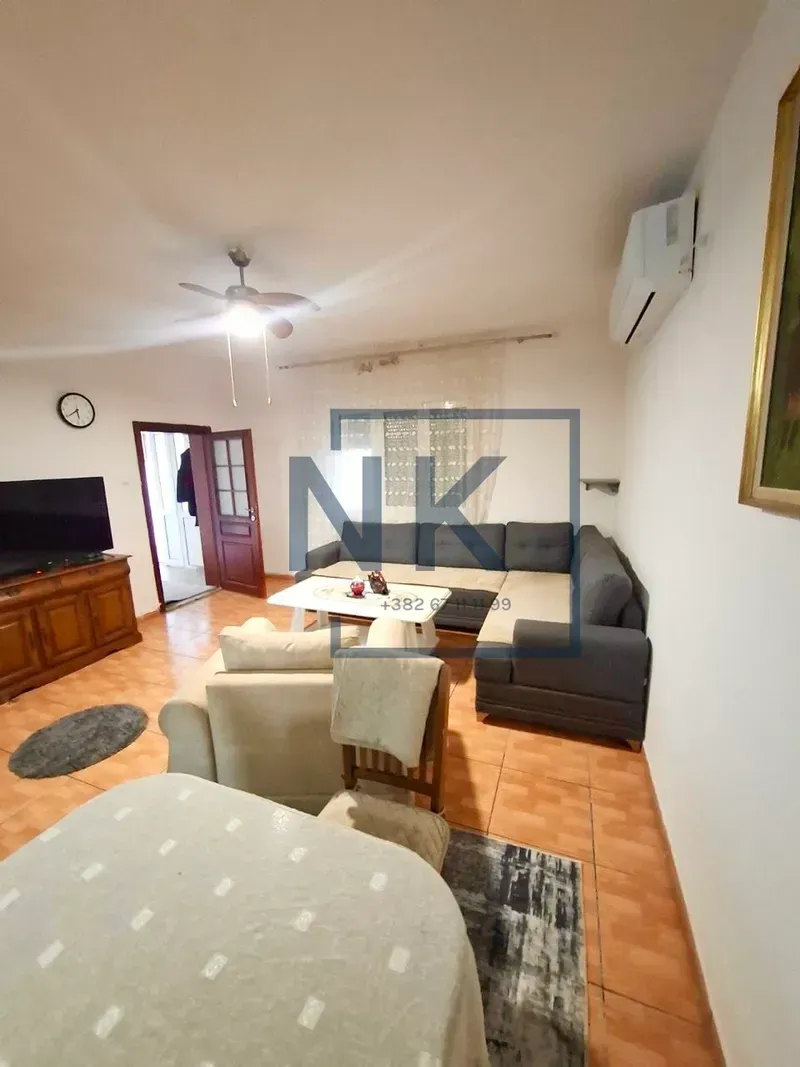 Living room with a sofa set, television, and dining table.