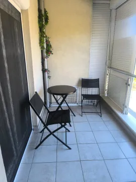 Small enclosed balcony with a table and two chairs. - image 7