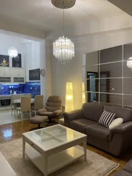 Bright living room with a leather sofa and kitchen in the background. - image 4
