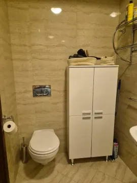 Pogled na kupatilo sa WC šoljom, bijelim ormarićem i bež pločicama. - image 5