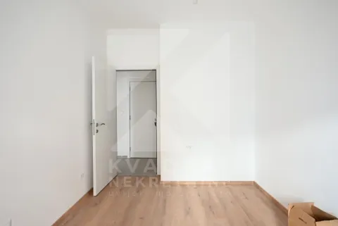 Prazna soba sa bijelim zidovima, drvenim podom i otvorenim vratima. - image 11