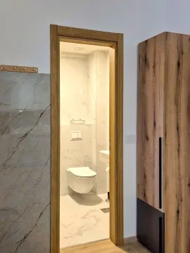 Pogled iz hodnika na moderno uređeno kupatilo sa pločicama sa efektom mermera. - image 10